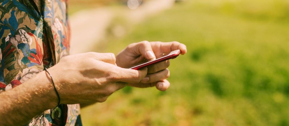 man-holding-smartphone-nature-min man-holding-smartphone-nature-min